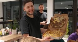 YouTuber How to be Human lacht mit einer Pizza in der Hand