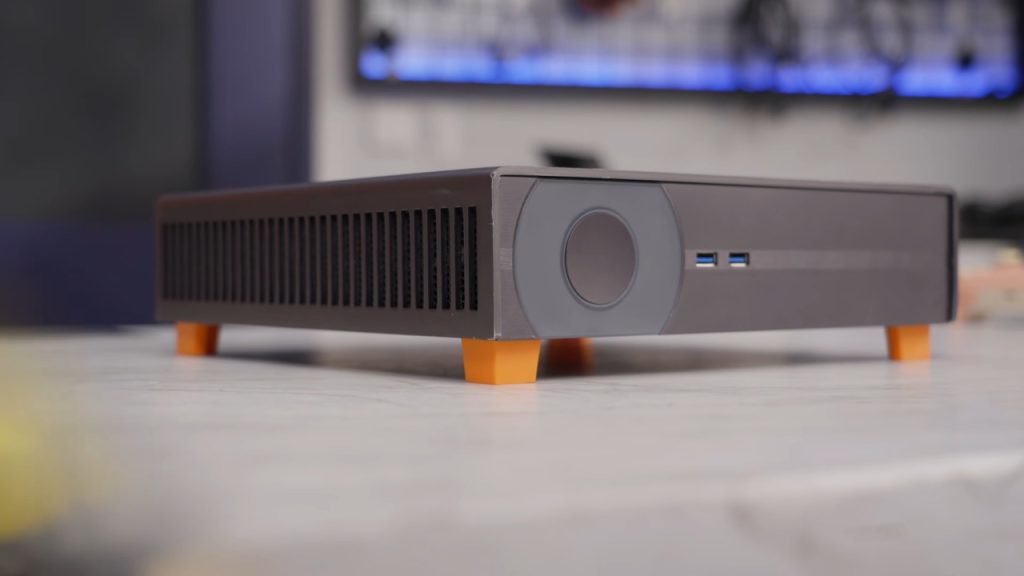 Screenshot aus dem YouTube-Video von Linus Tech Tips, der seine selbstgebaute Steam Machine zeigt. Das Gerät ist flach und steht auf 4 orangen Füßen.