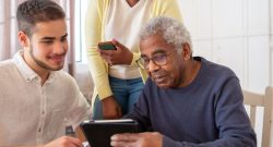 Junger Mann erklärt älteren Mann etwas auf dem Tablet
